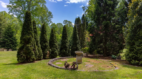 This expansive outdoor space features lush greenery and a unique stone birdbath, perfect for relaxation.