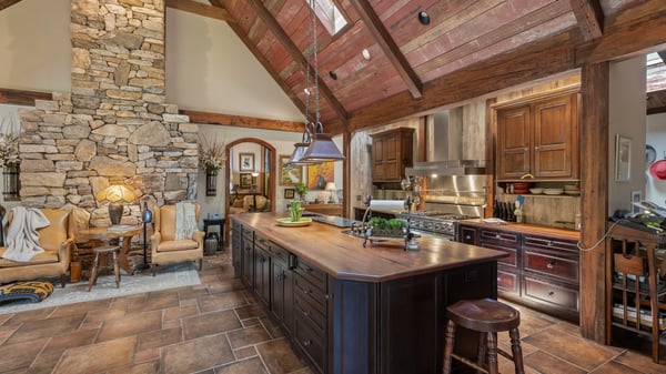 This spacious kitchen features a striking stone fireplace, high ceilings, and a large island for gatherings.
