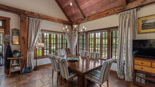 Inviting dining area featuring large windows, rustic beams, and ample space for gatherings or entertaining.