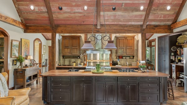 Discover this spacious kitchen featuring a large island, exposed beams, and rich wooden cabinetry, ideal for gatherings.
