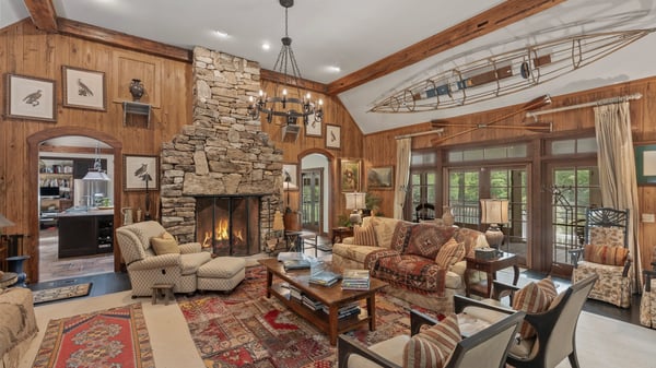 This cozy living room features a stunning stone fireplace, high ceilings, and abundant natural light.