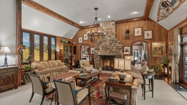 Spacious living area featuring a stunning stone fireplace and large windows with picturesque mountain views.