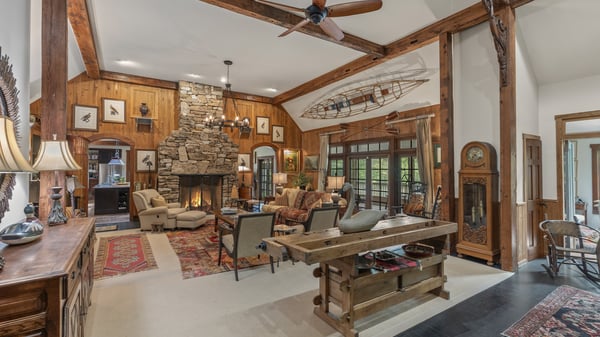 Discover a spacious living area featuring a striking stone fireplace and exposed wood beams, perfect for gatherings.