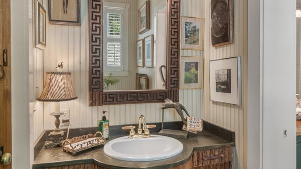 Unique bathroom featuring custom decor, artistic sink design, and a mix of vintage artwork for a personalized touch.