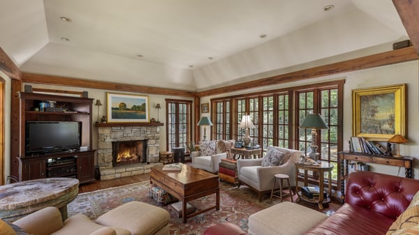 Spacious living room features abundant natural light, a cozy fireplace, and picturesque views through large windows.