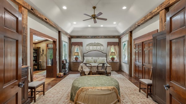 Spacious bedroom featuring rustic beams, large windows, and inviting seating, perfect for relaxation and comfort.