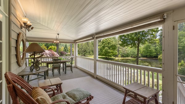 Discover this inviting covered porch, perfect for relaxing while enjoying views of the lush landscape and pond.