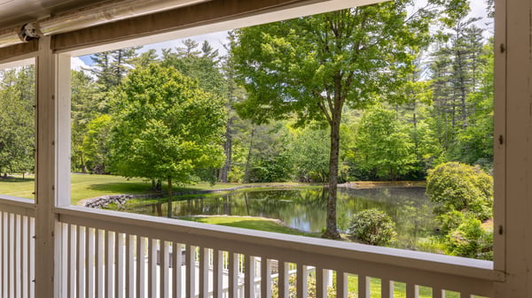 Beautiful views of a tranquil pond and vibrant greenery from the inviting covered porch.