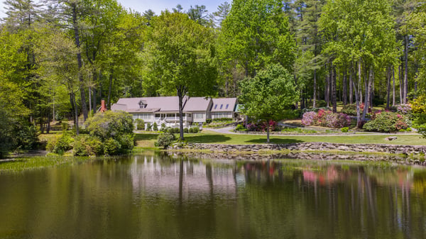 Idyllic waterfront property surrounded by lush greenery, featuring spacious interiors and picturesque landscaping throughout.