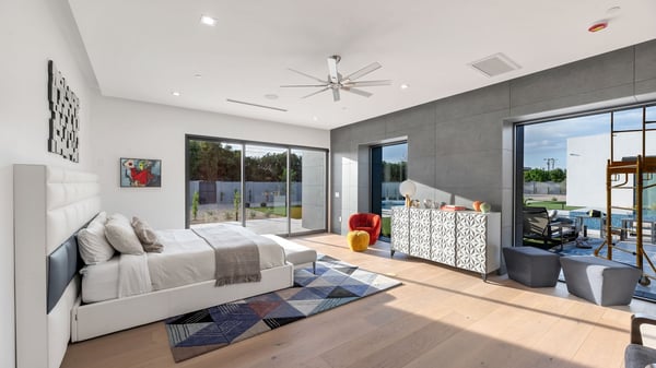 Elegant primary bedroom featuring large glass sliders, natural light, and seamless connection to outdoor living spaces. This Paradise Valley retreat blends comfort with modern design.
