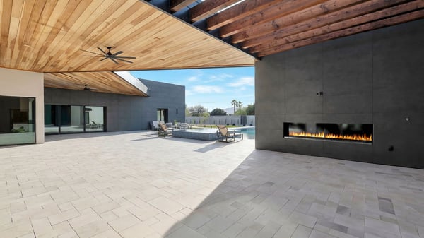Covered outdoor living space with wood-paneled ceiling, sleek fireplace, and views of the pool area. This Paradise Valley home is designed for luxury outdoor entertaining and relaxation.