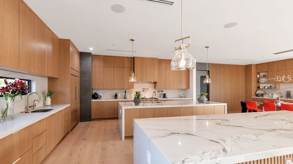 Contemporary kitchen featuring two oversized islands, quartz countertops, and custom cabinetry. This Paradise Valley residence offers high-end finishes and an entertainer-friendly layout.