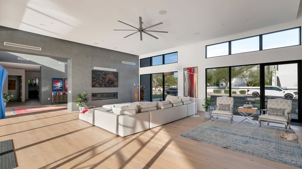 Open great room with tall ceilings, expansive windows, and modern fireplace wall. This Paradise Valley home offers a bright and airy living space.
