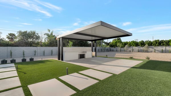 Backyard featuring covered trellis, built-in outdoor kitchen, and green turf areas. This Paradise Valley home is perfect for hosting and outdoor gatherings.