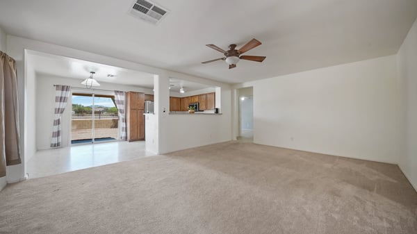 Spacious living room offers neutral finishes, plush carpet, ceiling fan, and a bright open layout ready for your personal design. The seamless flow enhances both comfort and functionality.