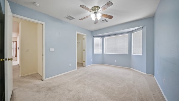 Spacious primary bedroom enjoys a large bay window, ceiling fan, plush carpeting, and direct access to the ensuite bath. A peaceful retreat with plenty of room to personalize.