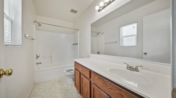 Ensuite bathroom features a long vanity, oversized mirror, combination tub and shower, and natural light. Designed with comfort, convenience, and everyday functionality in mind.