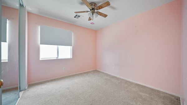 Secondary bedroom offers natural light, mirrored closet doors, plush carpeting, and flexible space suitable for guests, family members, or a home office in this Buckeye home.