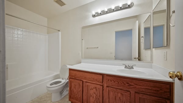 Hall bathroom includes a full tub and shower combination, large vanity, oversized mirror, and easy-care finishes. A functional space that comfortably accommodates family and guests alike.