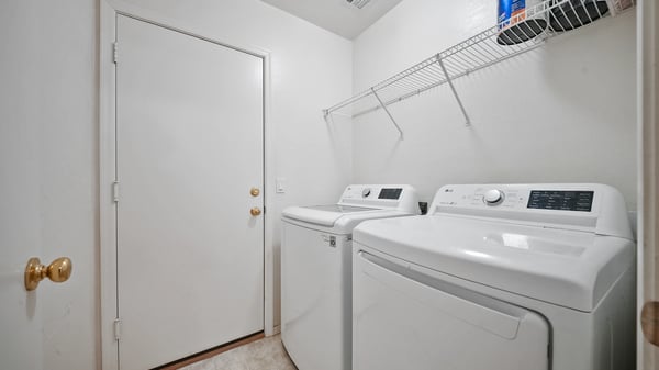 Well-designed laundry room includes washer and dryer, built-in shelving, and convenient access to the backyard. A practical feature that enhances everyday living.