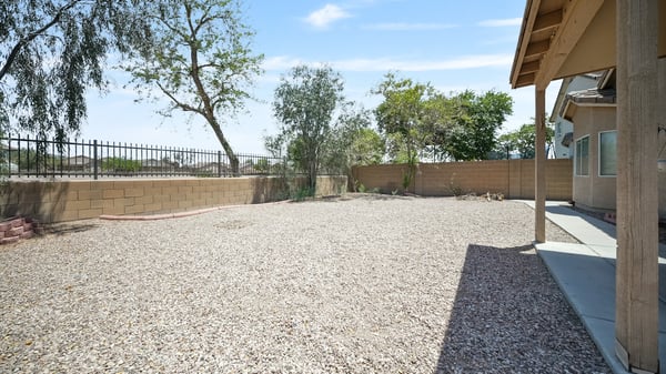 Large backyard provides a covered patio, mature shade trees, and low-maintenance landscaping with ample room to customize your outdoor lifestyle in Buckeye.