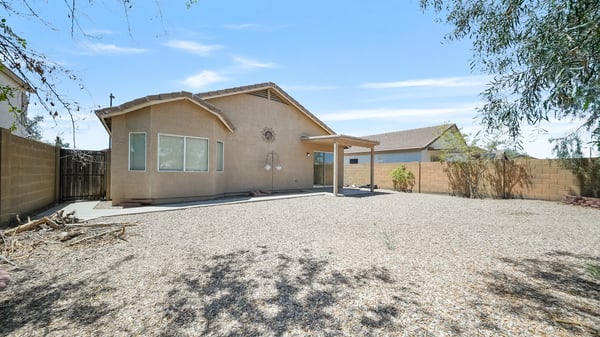Rear exterior showcases the covered patio and spacious backyard with plenty of room to relax, entertain, or personalize with future landscaping and outdoor amenities.