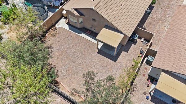 Bird's-eye view captures the backyard layout, covered patio, mature landscaping, and spacious outdoor area, providing an excellent perspective of the property's generous rear yard.