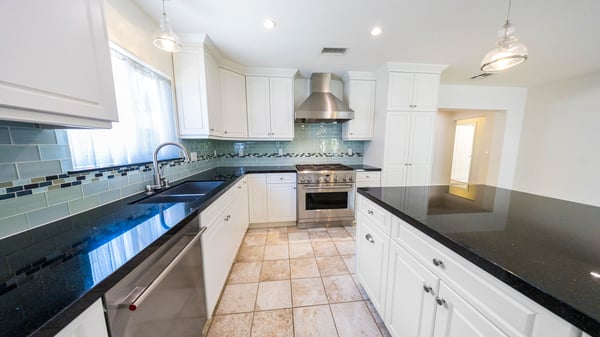 Large chef's kitchen with granite countertops, glass tile surround
