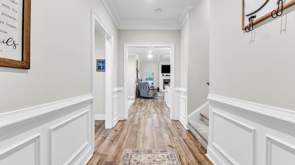 Bright and inviting hallway features modern trim and LVP flooring, leading to a cozy living area.