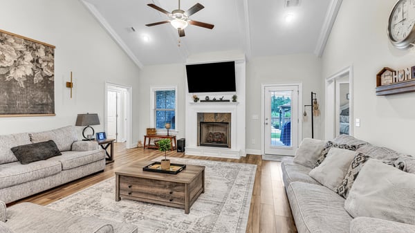 Spacious living area with vaulted ceilings, a cozy fireplace, and abundant natural light throughout.