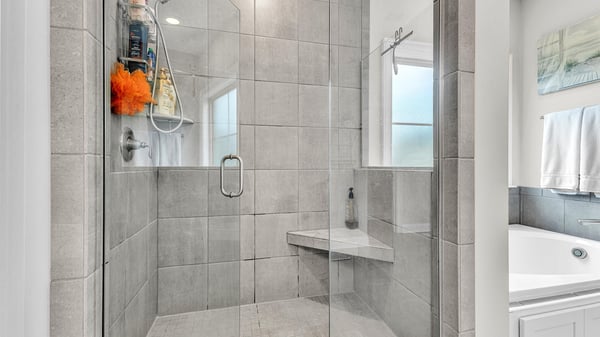 Modern walk-in shower featuring sleek glass doors, ample natural light, and convenient bench seating.