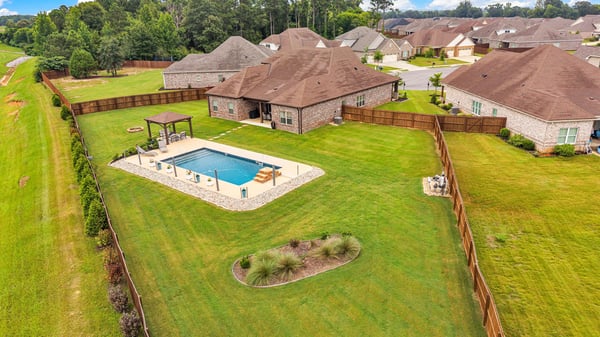 Spacious backyard oasis featuring a pool, pergola, and ample room for outdoor gatherings and activities.