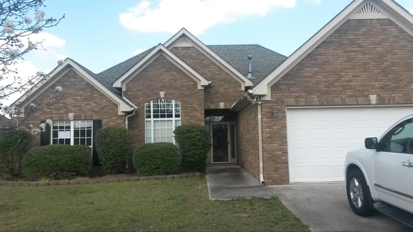 Spacious brick home featuring ample front yard, modern garage, and inviting entrance in a quiet neighborhood.