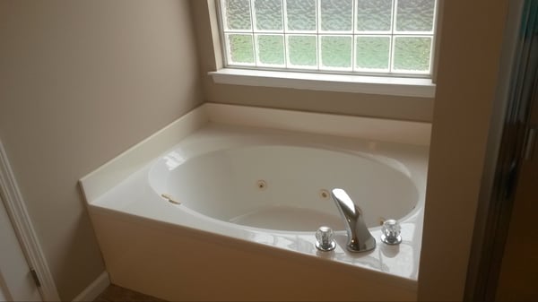 Relax in this spacious bathtub with natural light pouring in through the glass block window.