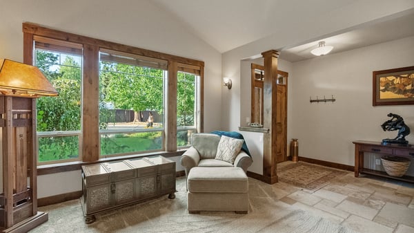 Bright and inviting entryway featuring large windows, natural light, and a cozy seating area.
