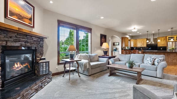 Spacious living room featuring a cozy fireplace, large windows, and an open layout to the kitchen.