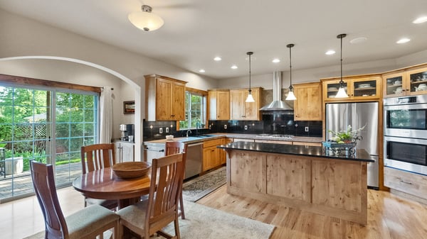 Bright, open kitchen featuring natural wood cabinetry, stainless steel appliances, and seamless access to outdoor space.