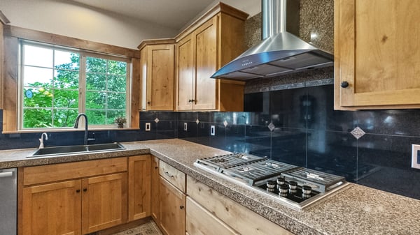 Modern kitchen featuring natural wood cabinetry, sleek countertops, and a window that welcomes abundant light.