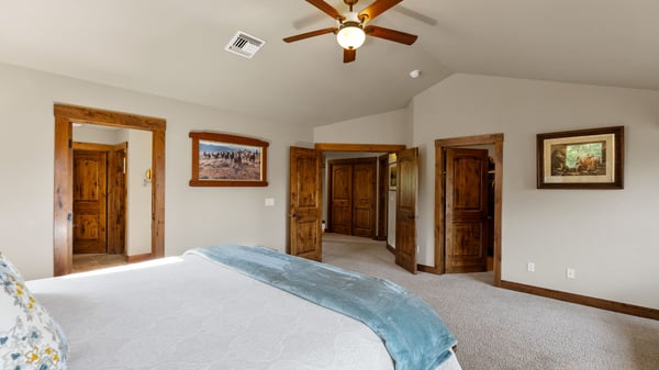 Spacious bedroom featuring vaulted ceilings, natural light, and quality wood accents throughout for a warm atmosphere.