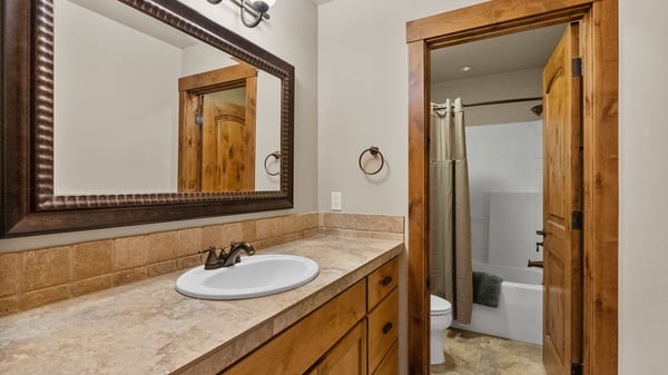 Bright bathroom featuring a spacious countertop, ample storage, and a combination tub/shower for convenience.