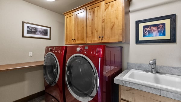 This functional laundry room features modern red appliances, ample storage, and convenient countertop space.