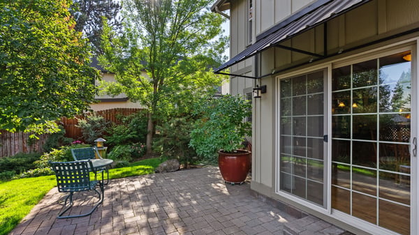 Inviting outdoor space features a quaint patio surrounded by lush landscaping and vibrant greenery.