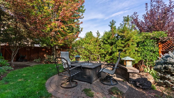 Discover a tranquil backyard retreat featuring brick pathways, lush landscaping, and cozy seating for outdoor gatherings.