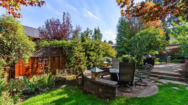 Lush backyard retreat featuring a brick patio, diverse landscaping, and ample space for relaxation and gatherings.
