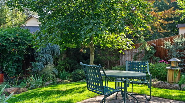Enjoy outdoor dining in this lush garden, featuring a cozy seating area surrounded by vibrant greenery.