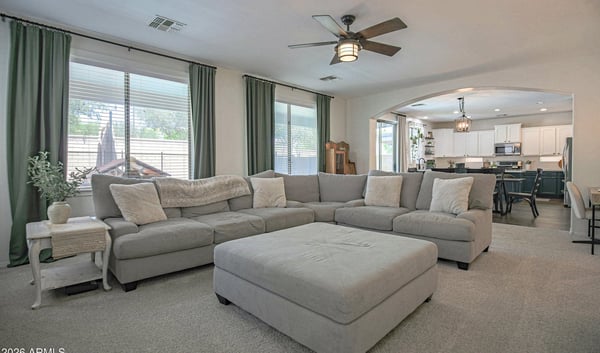 Spacious family room with plush carpeting, oversized windows, and an open layout connecting seamlessly to the kitchen. Perfect for entertaining guests or relaxing with family.