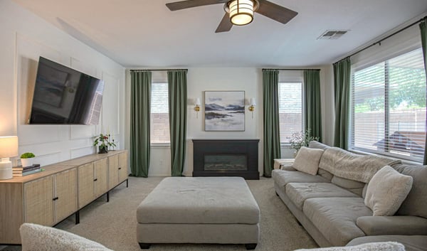 Inviting family room featuring a cozy fireplace, elegant accent wall, large windows, and an open layout. A perfect space to gather, unwind, and enjoy everyday comfort in this Waddell home.