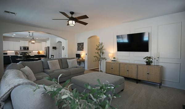 Beautiful family room with custom wall accents, plush carpeting, and an open layout connecting effortlessly to the kitchen. A welcoming space designed for relaxing and spending time together.