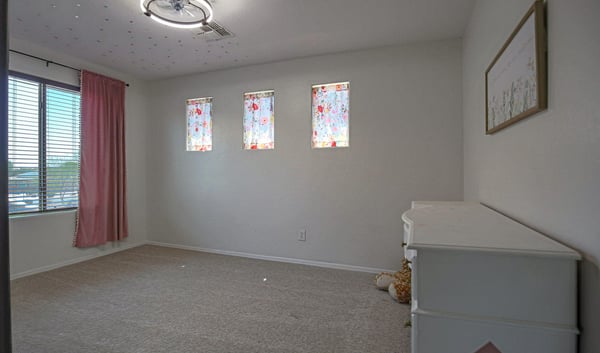 Bright secondary bedroom with plush carpeting, large windows, and flexible space for guests, children, or a dedicated home office in this move-in-ready Waddell property.