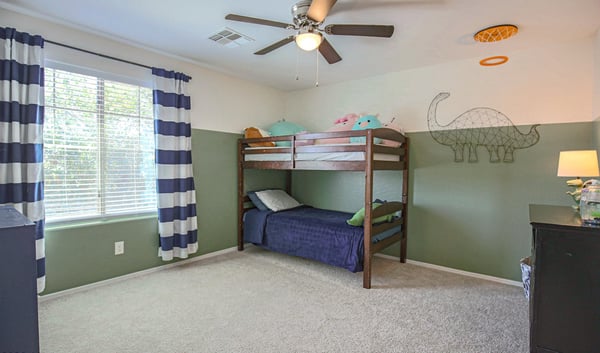 Large bedroom with plush carpeting, ceiling fan, and oversized window creating a bright, cheerful space. Perfect for children, guests, or a flexible bonus bedroom.